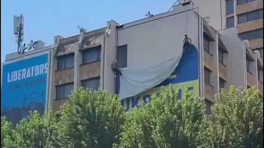 Великий синьо-жовтий український банер на будівлі у центрі Приштини та момент його зняття
